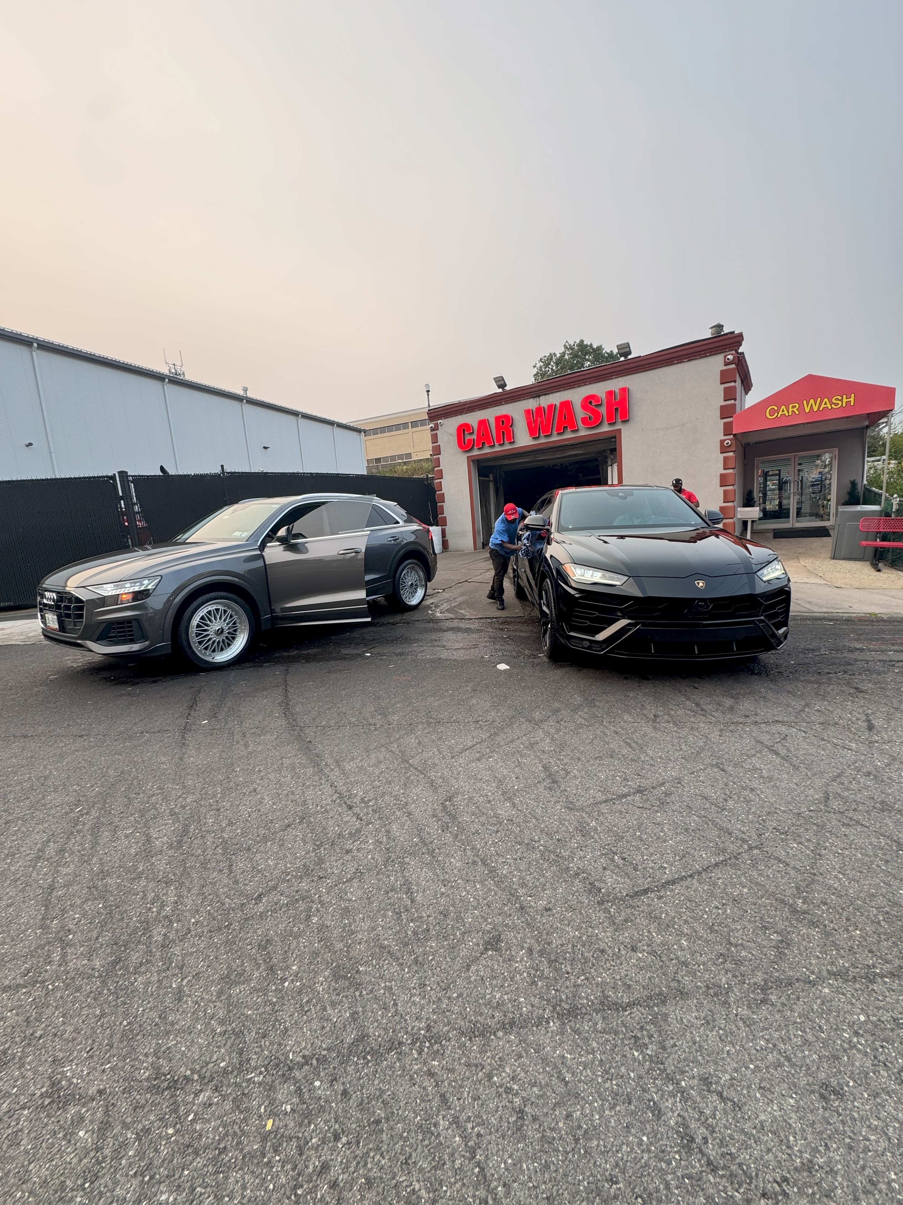 Two luxury cars at the Yonkers Car Wash storefront under the CAR WASH signs